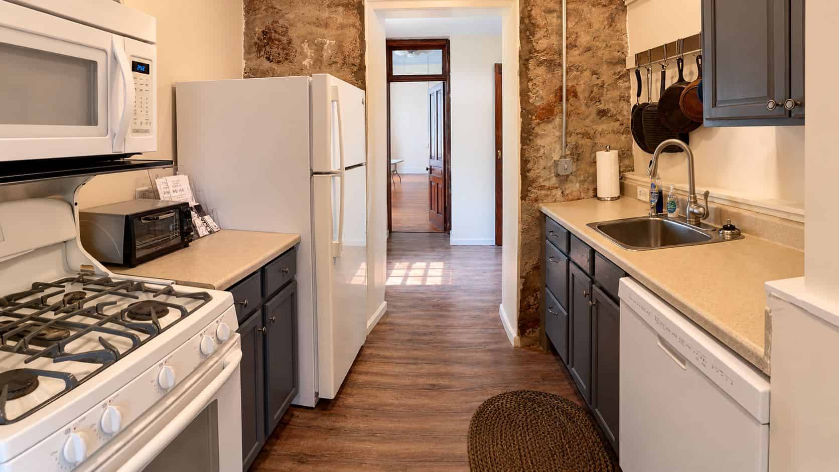 Venue 272 Kitchen Modern kitchen with light gray cabinets, stainless steel appliances, exposed wooden ceiling beams, and light wood flooring.